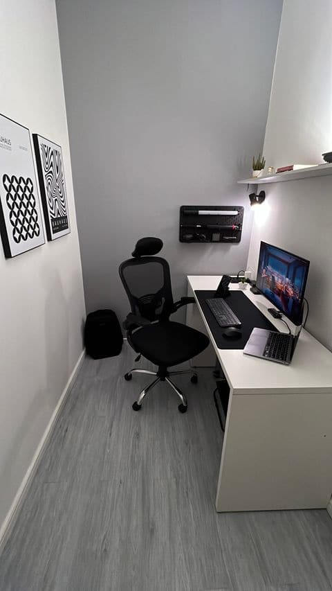 Escritório da Origem com mesa branca, cadeira ergonômica, monitor e notebook